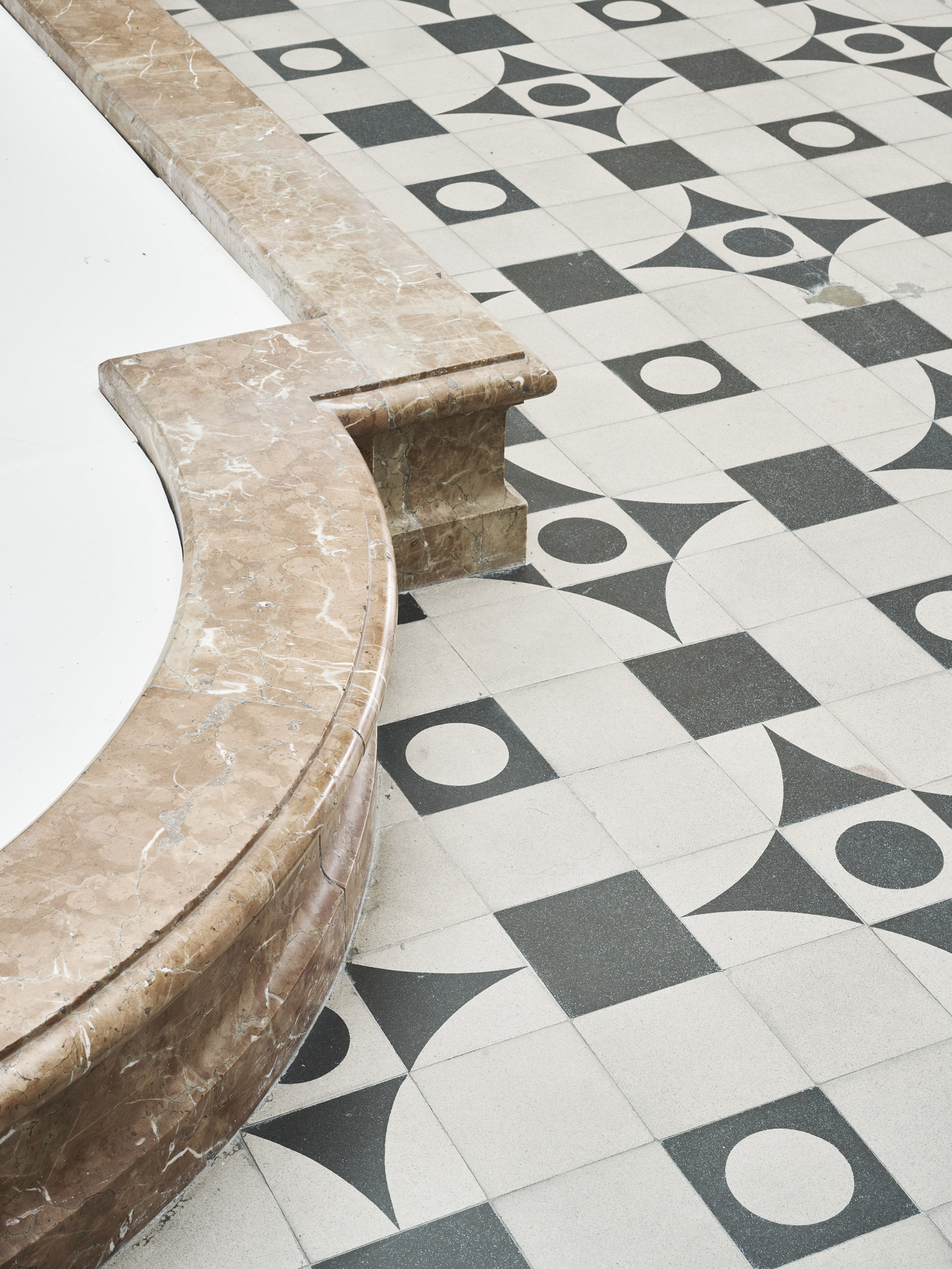 Foto der Rathausgalerie: Ausschnitt mit schwarz-weiß gefließtem Boden. Auf der linken Seite ist ein Teil des rotfarbenen Brunnenbeckens zu erkennen. 