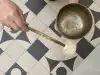 View from above - a singing bowl is struck above a black and white tiled floor with ornaments.